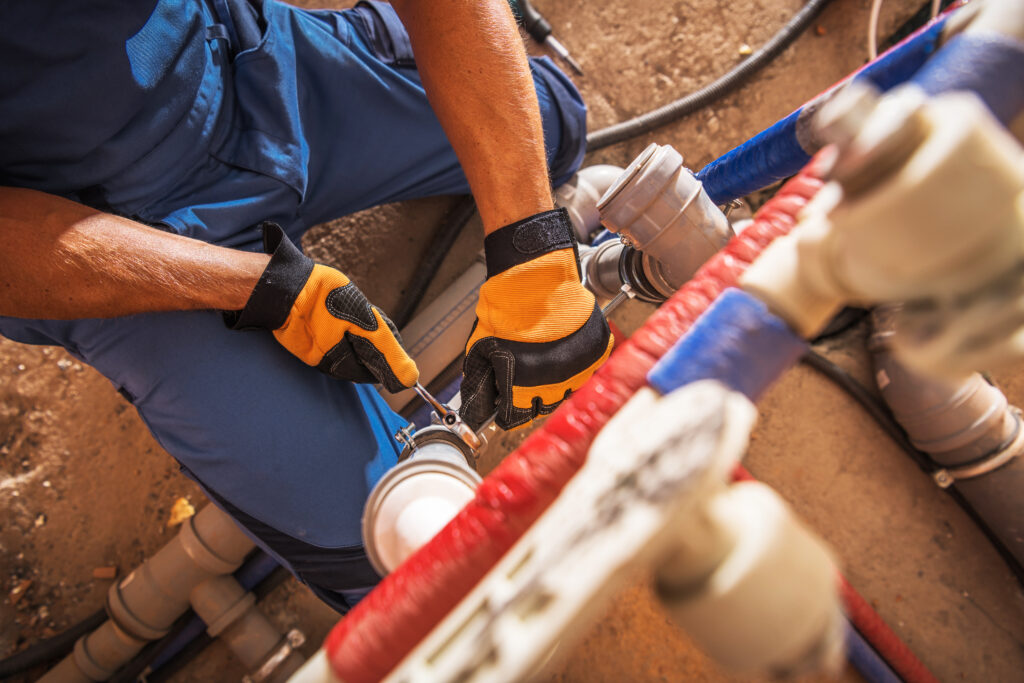 Plumber repairing water line with tools and pipes